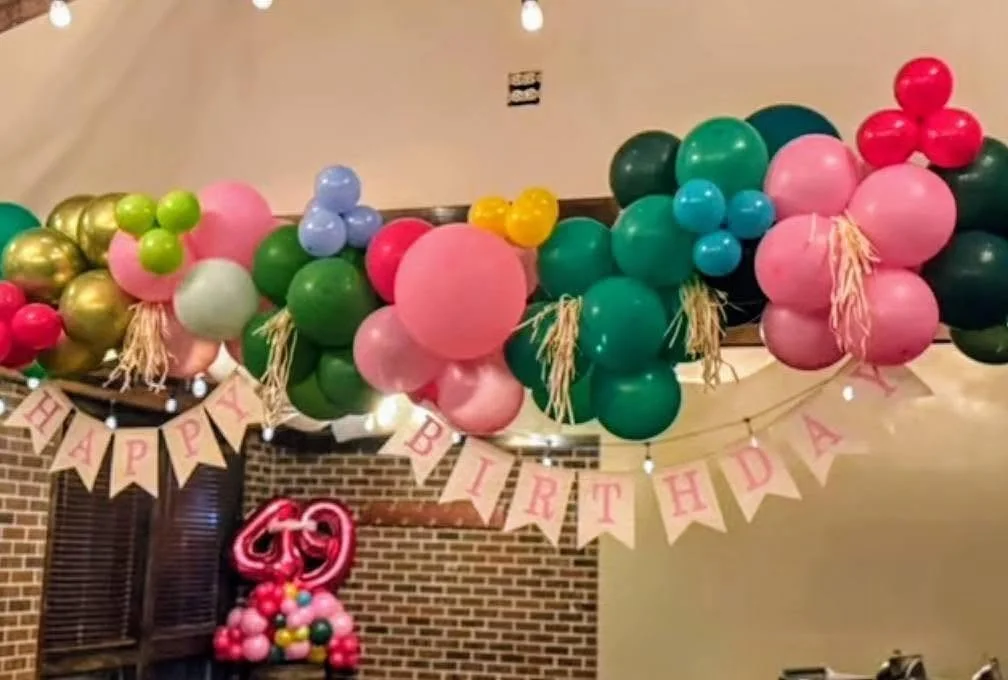 Colorful balloon garland and “Happy Birthday” banner decorating an indoor birthday party.