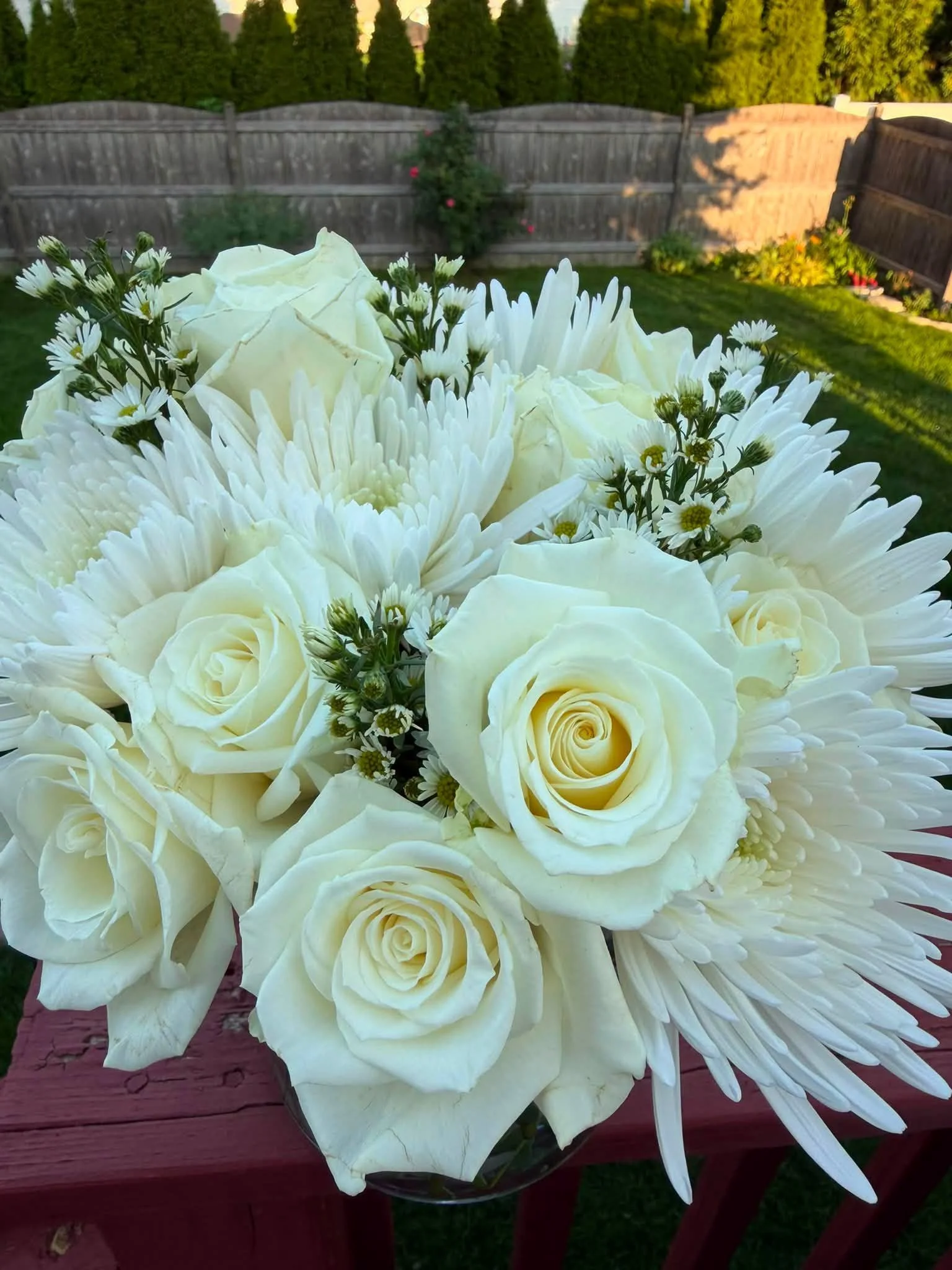 Bouquet of white roses, chrysanthemums, and small daisy flowers in a backyard garden