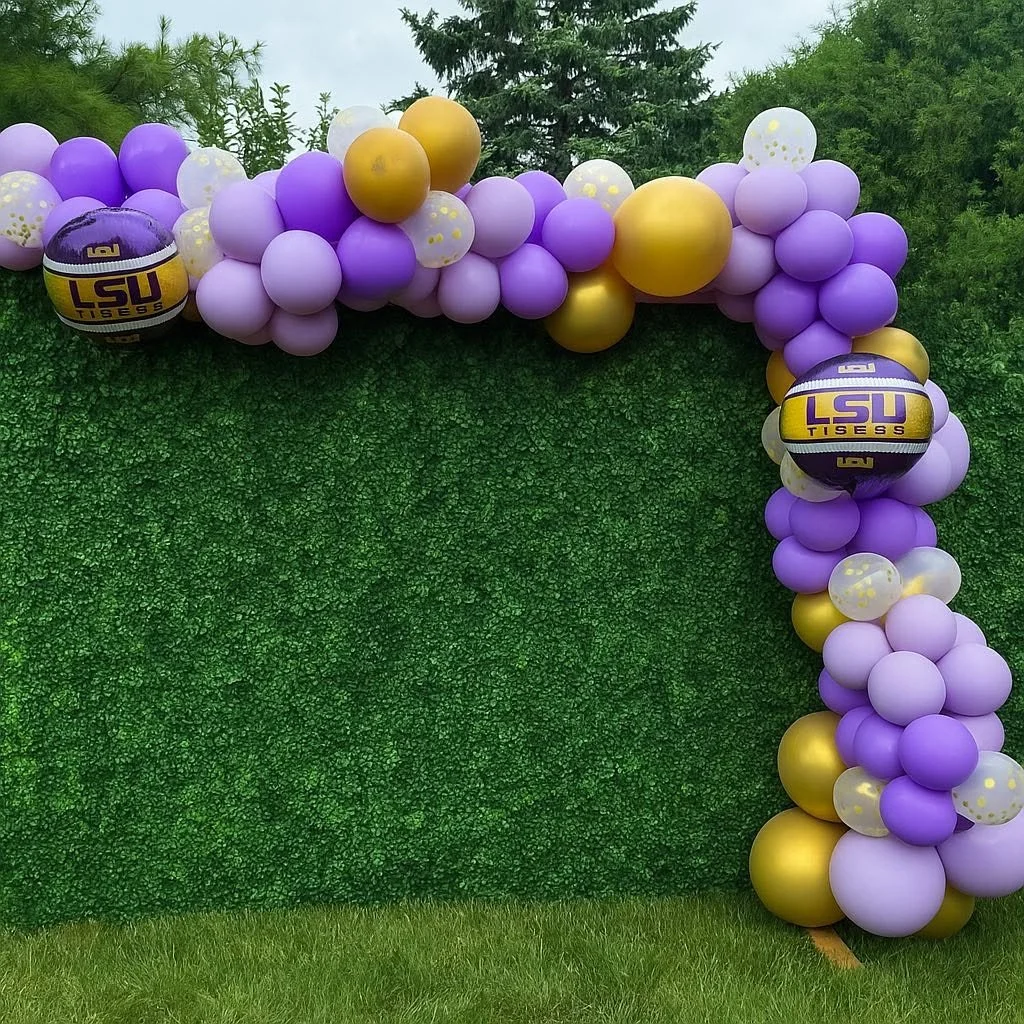 Purple, gold, and lavender balloon arch with two LSU Tigers basketballs against a green boxwood backdrop