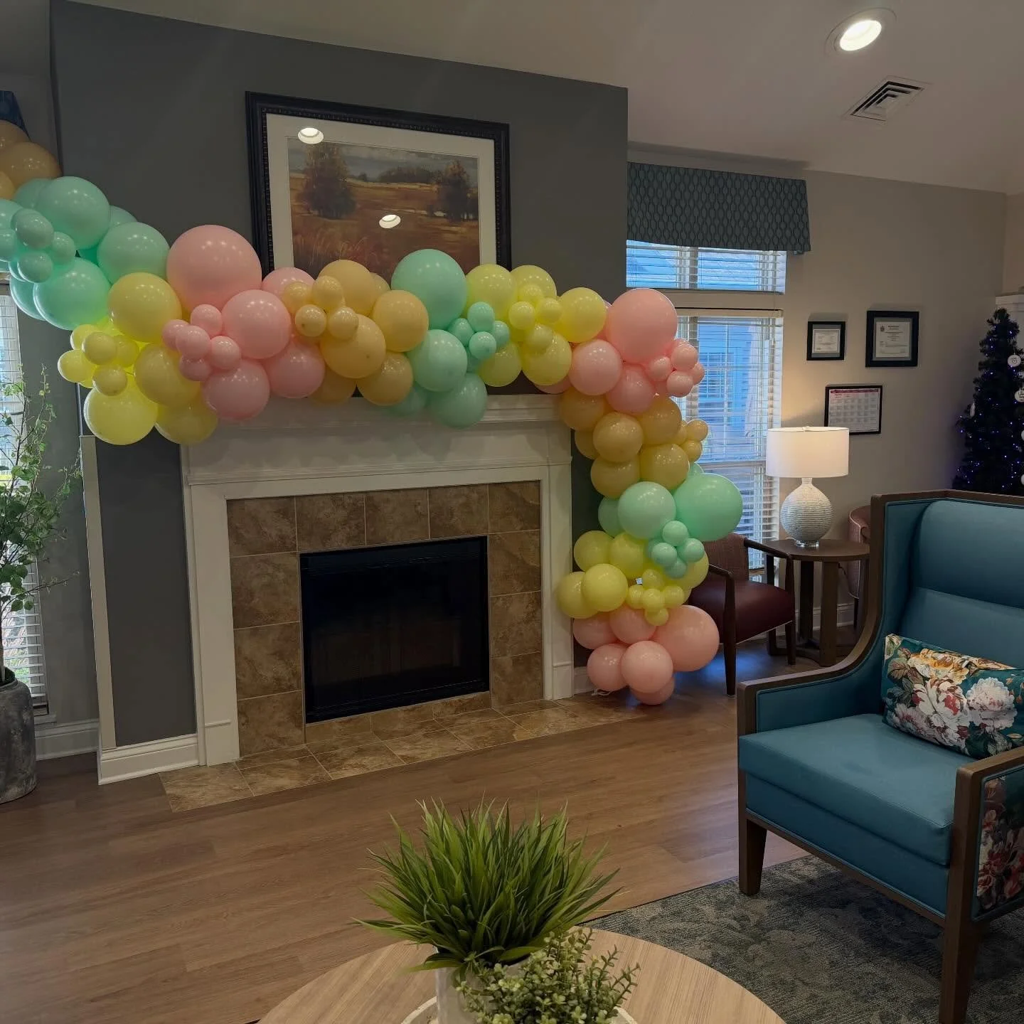 Pastel balloon garland decorating a fireplace in a cozy living room
