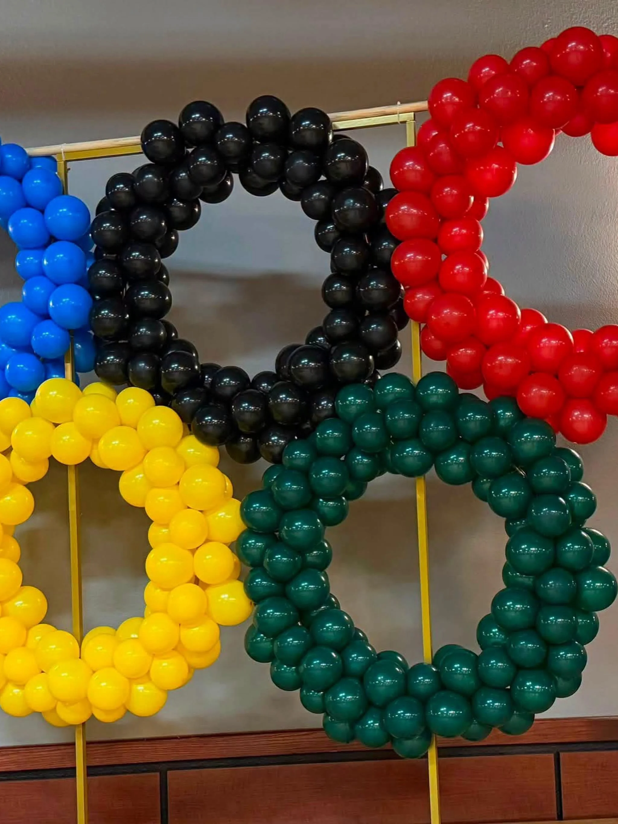 Colorful balloon arch with blue, yellow, black, red, and green sections mounted on a rectangular frame.