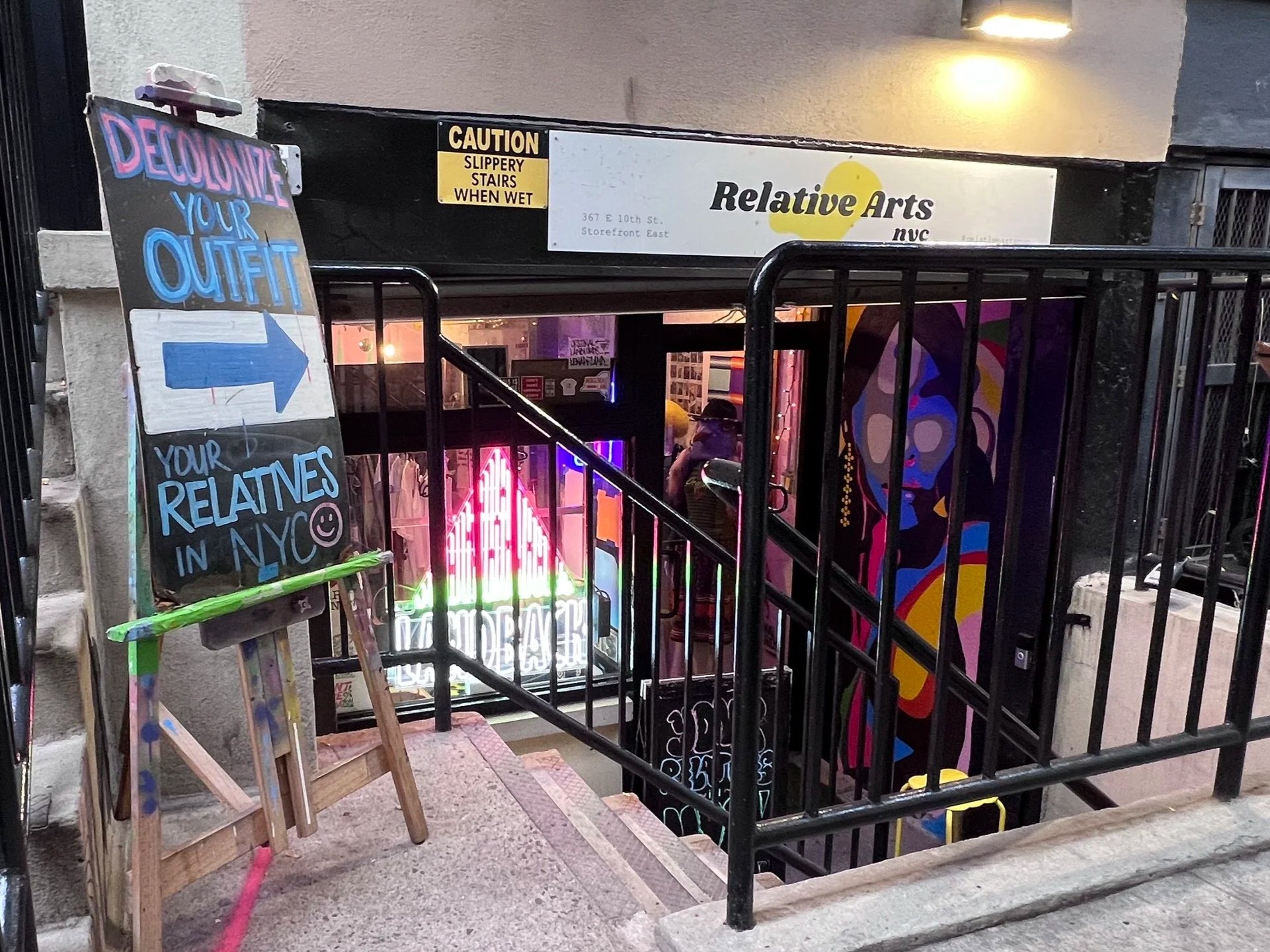 Entrance to Relative Arts NYC storefront at 367 E 10th Street, with colorful artwork, neon lighting, and a sign reading “Welcome your outfit, your relatives in NYC.”