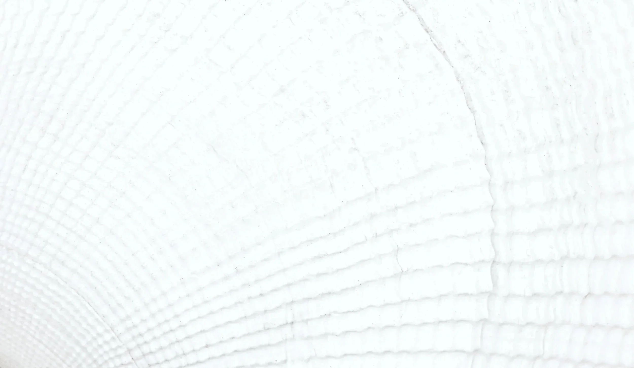 Close-up image of a white textured cloth or paper surface with embossed or woven pattern.