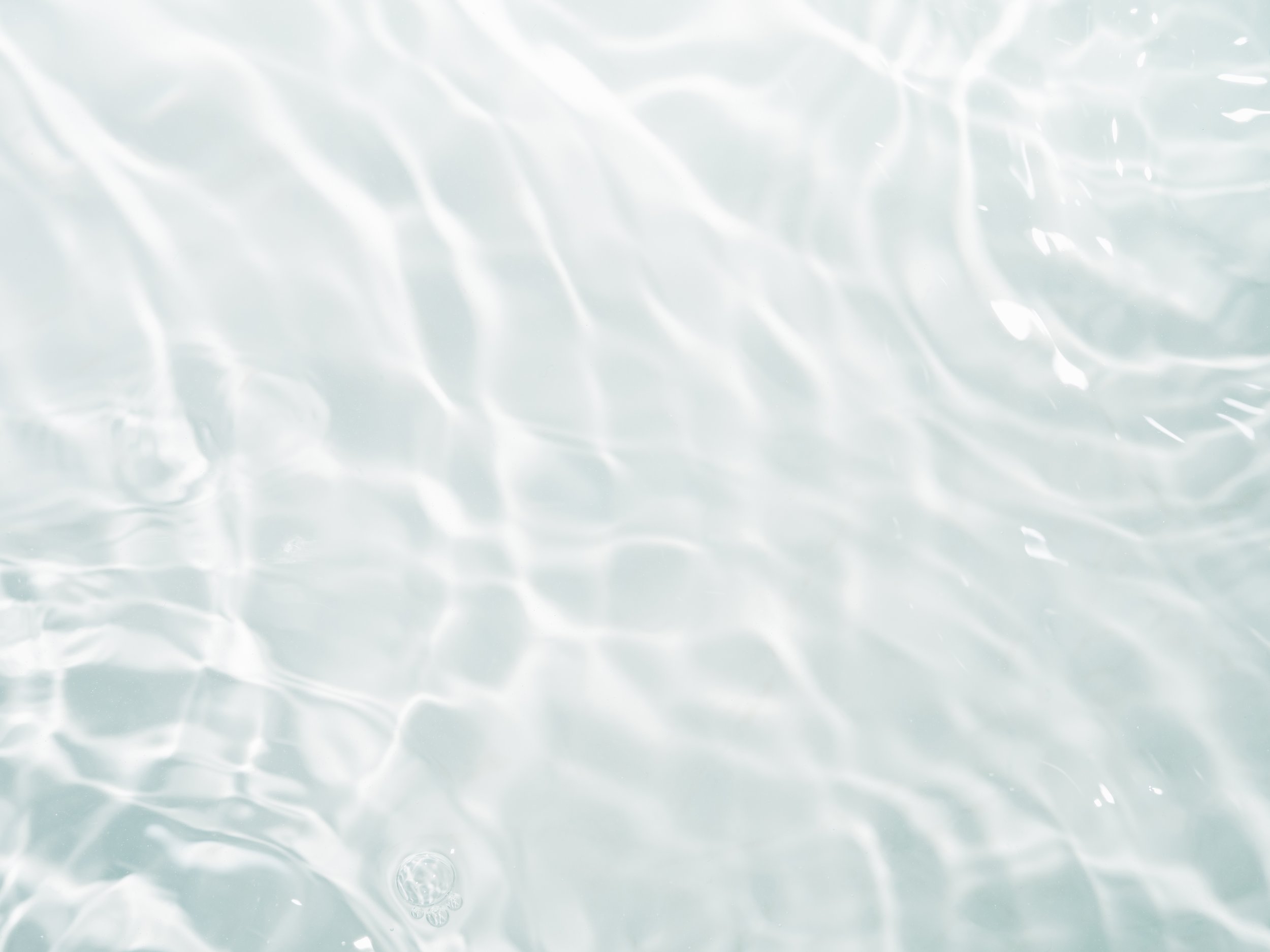 A close-up view of the surface of water with light reflections creating a rippling pattern.