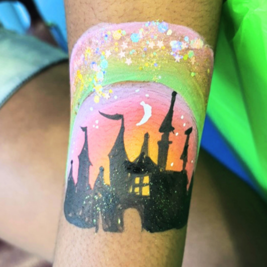 Tattoo of a haunted castle with spires on a pink and yellow gradient background with stars and a crescent moon.