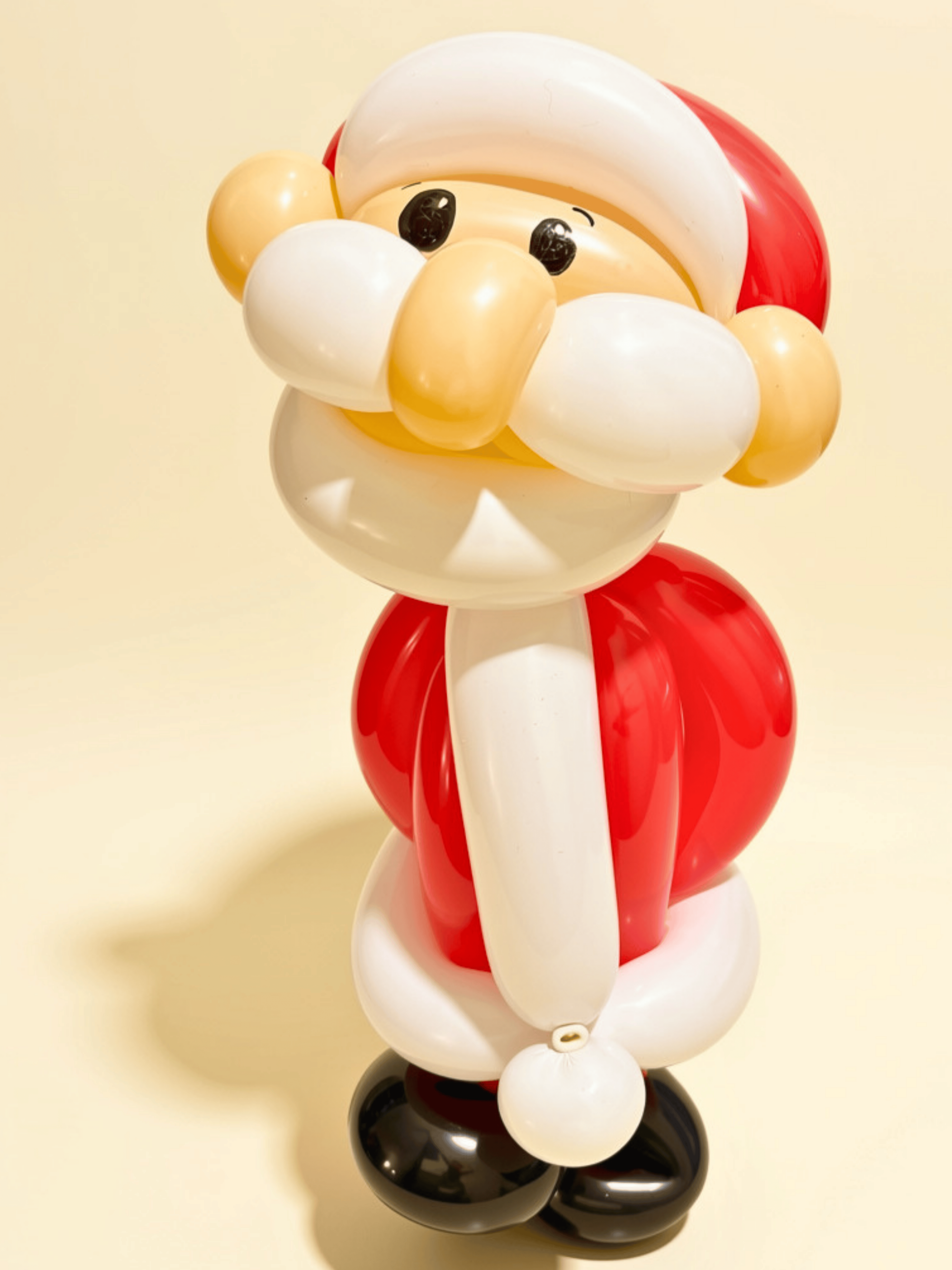 Balloon sculpture of Santa Claus with a white beard, red hat, and black boots, made from balloons.