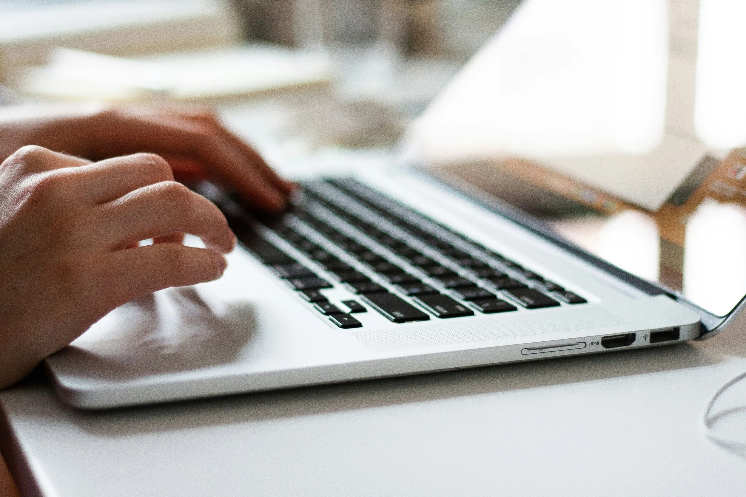 Close-up of hands typing on a laptop keyboard.