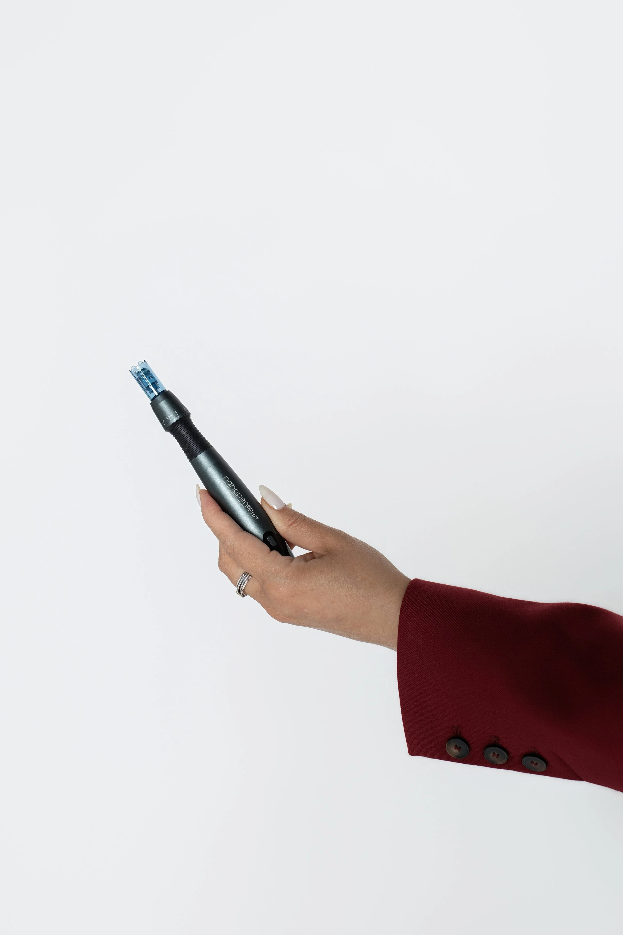 A person's hand holding a black pen with a blue cap against a plain white background, with part of the person's red sleeve and gray jacket sleeve visible.