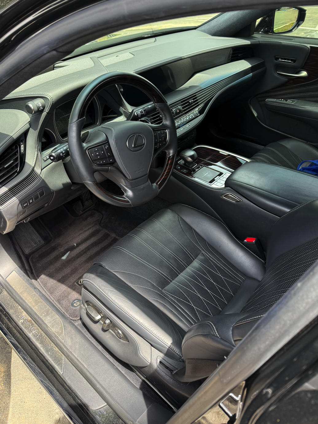 Interior of a Lexus vehicle, showing leather seats, steering wheel, dashboard, center console, and gear shift.