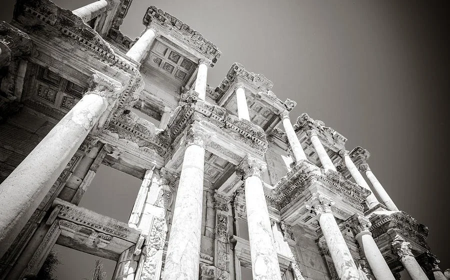 Ancient Roman ruins with tall marble columns and detailed stone architecture, viewed from below.