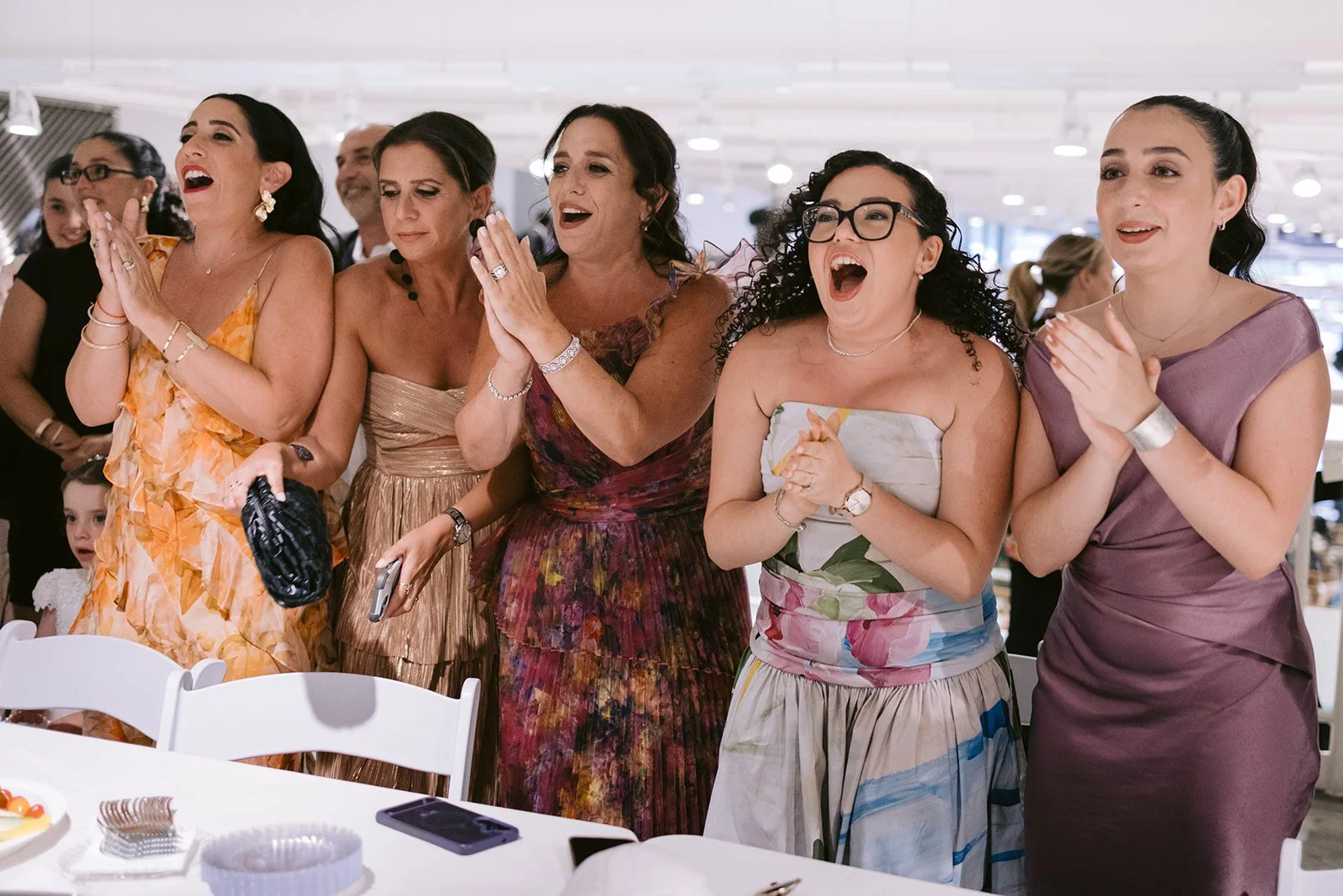 Bridesmaids in dresses of mixed colors cheer and applaud at Kaleigh and Noah's wedding