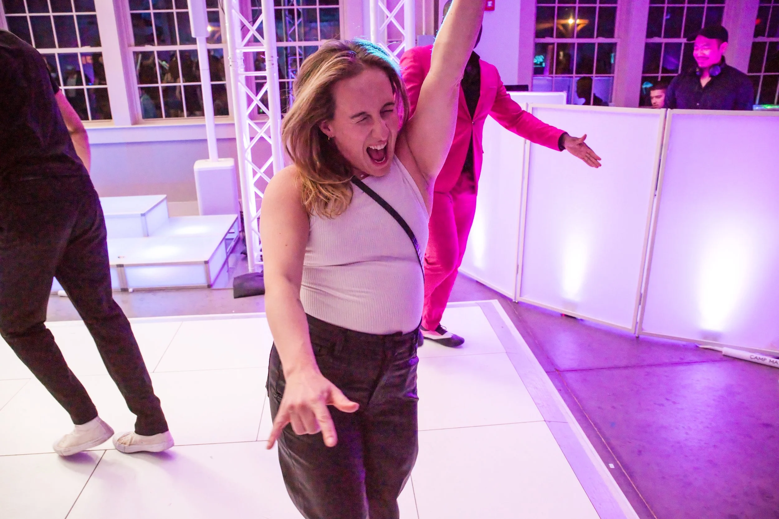 A guest dances with one arm in the air on the lit dance floor at the Camp Ramah bat mitzvah