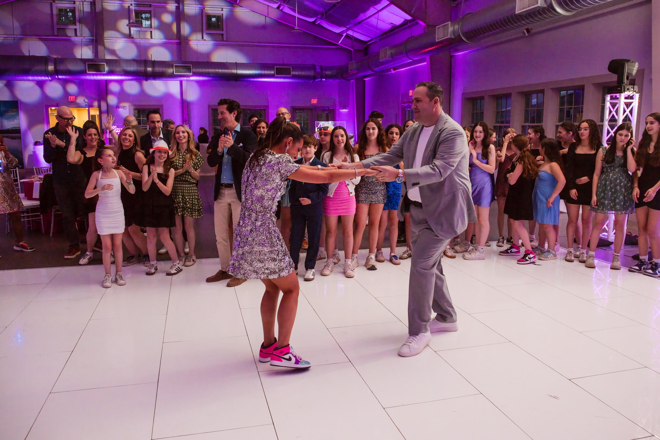 A guest and a dancer take the center of the dance floor while kids cheer around them at the Camp Ramah bat mitzvah