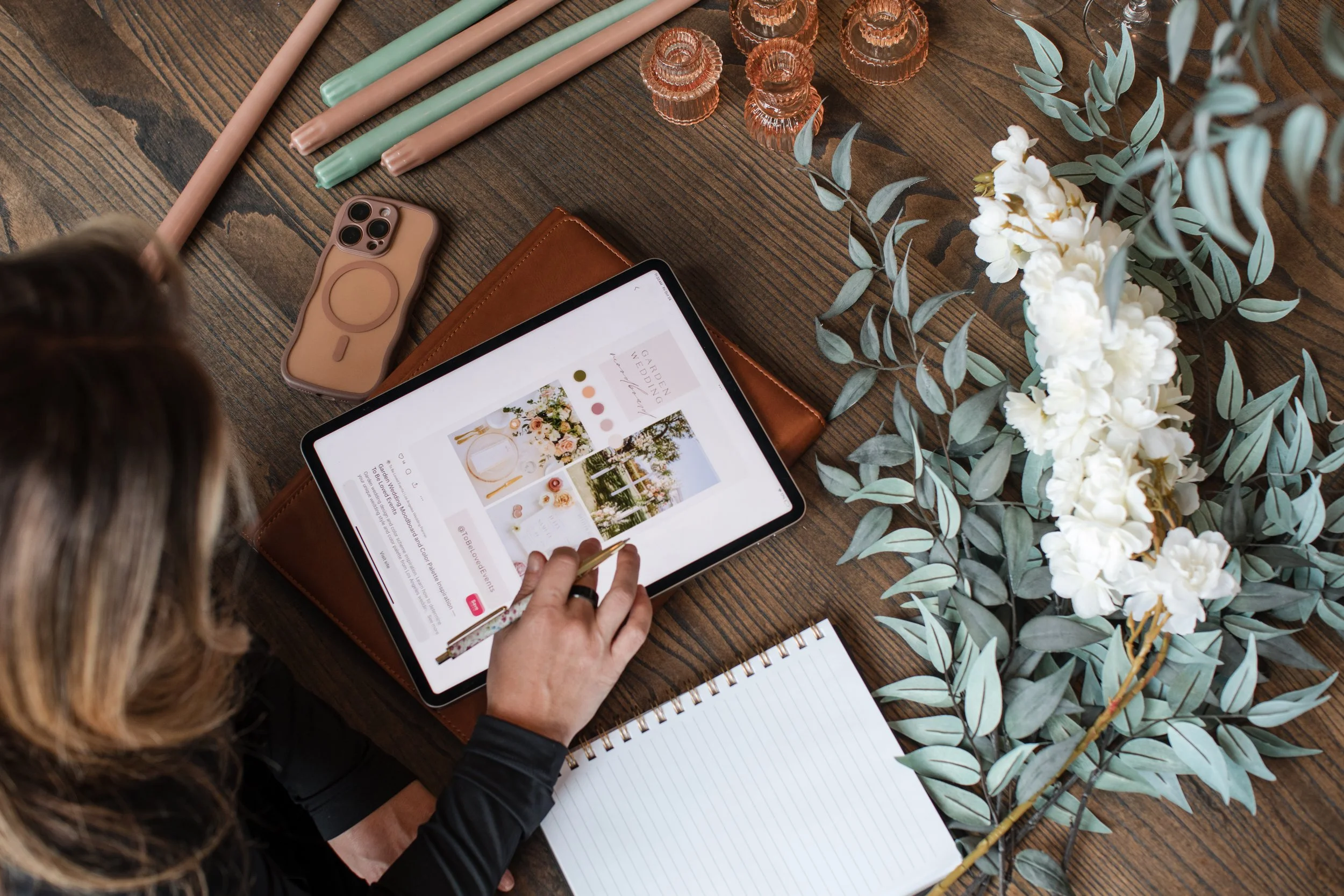 Wedding planning mood board on a tablet surrounded by flowers and greenery