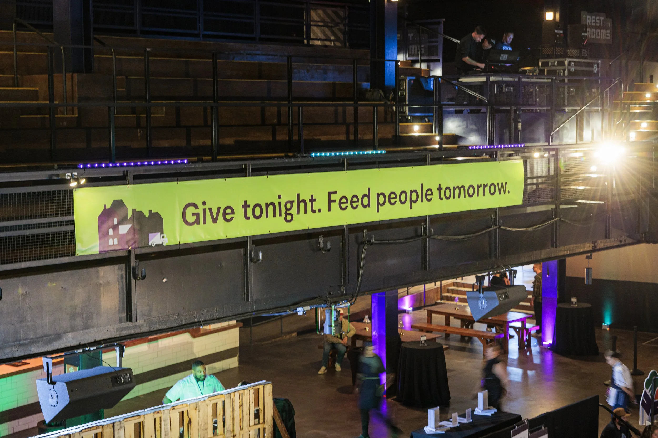 A Give tonight. Feed people tomorrow. banner hangs from the balcony inside the Roadrunner venue