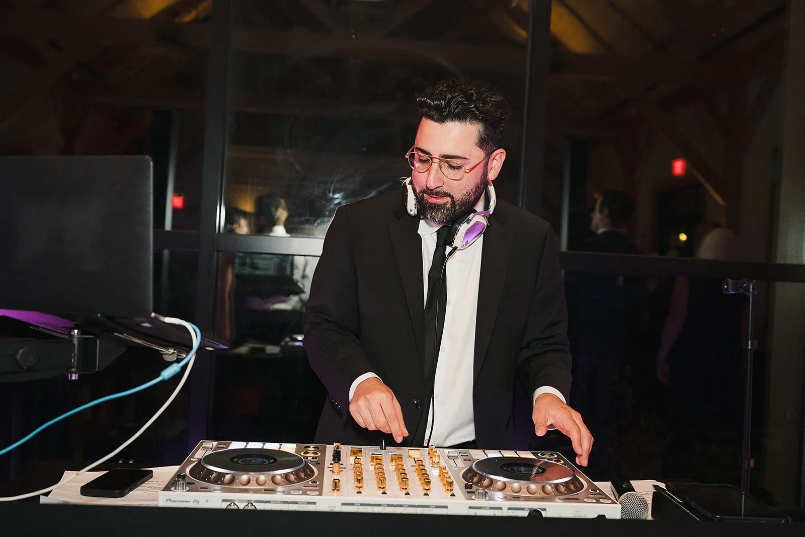 A DJ in a suit mixes at the turntables during the wedding reception