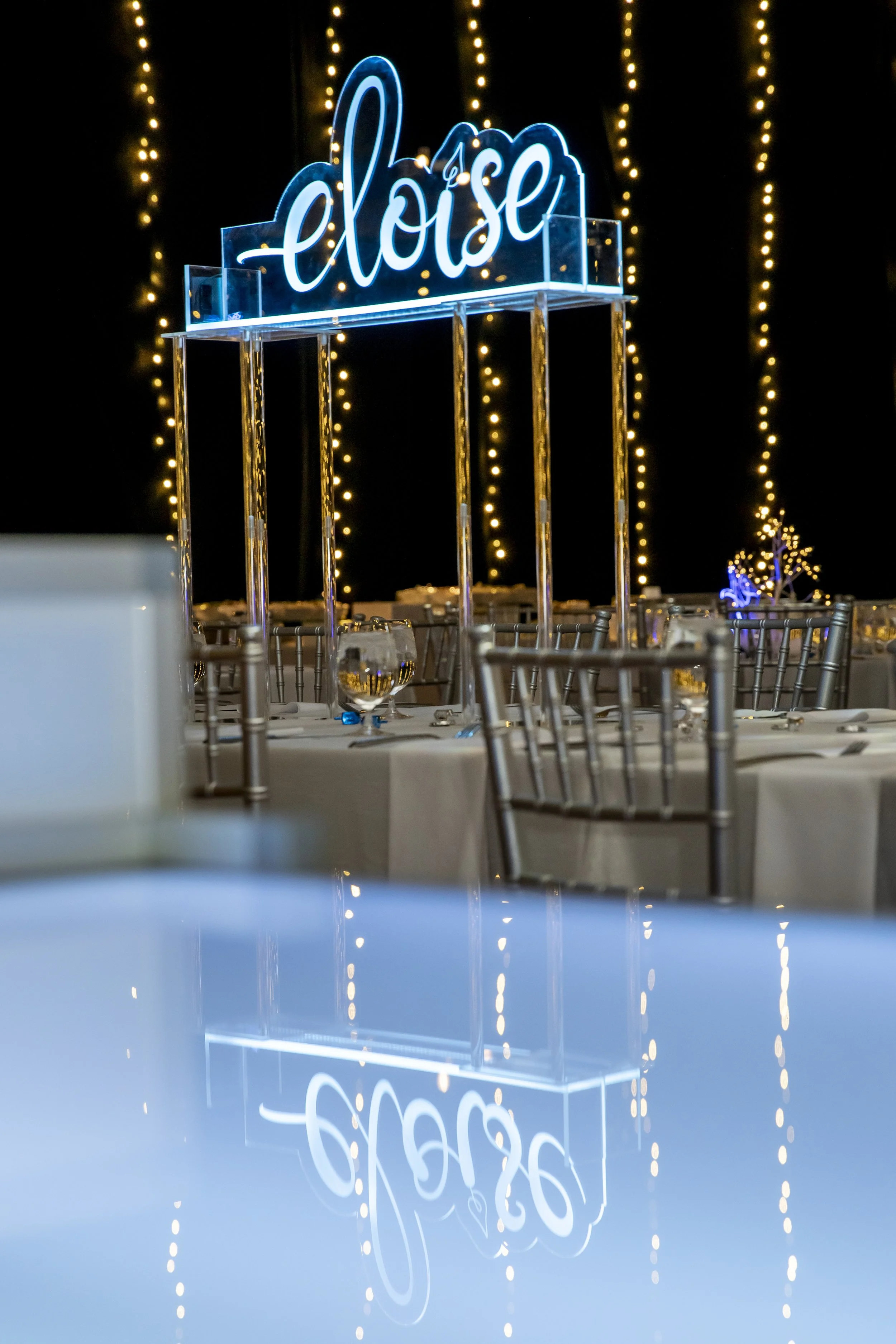 A neon-style eloise sign glows above a reflective table at the light-up bat mitzvah in Boston