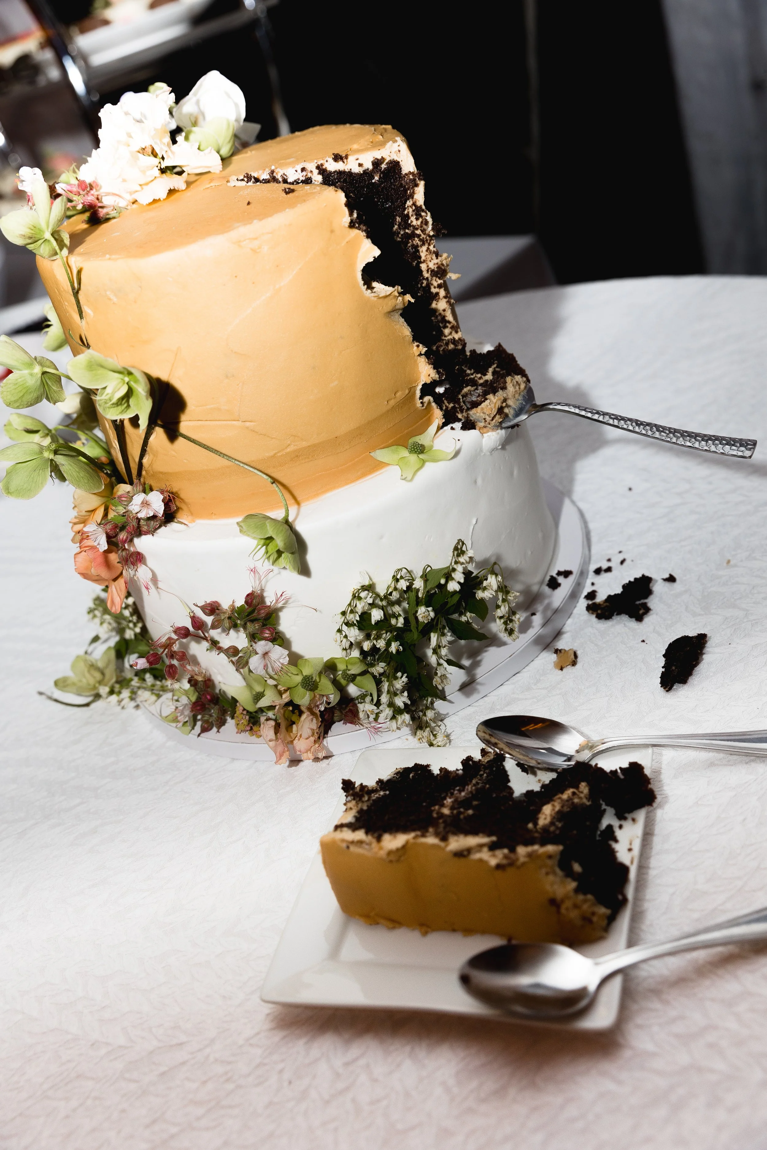A caramel-frosted wedding cake with chocolate layers, cut and served beside a slice on a plate