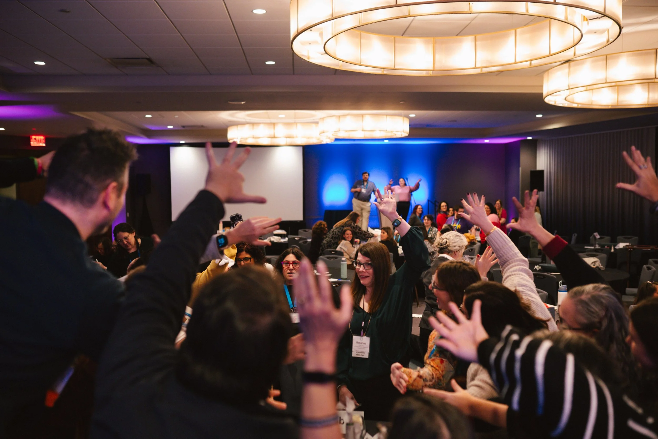 Guests raise their hands and cheer in a packed ballroom at the ARJE conference