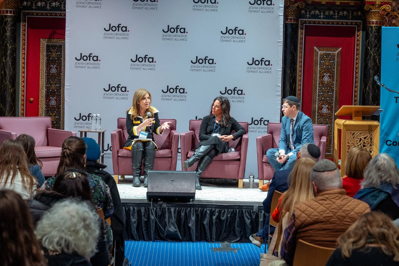 Three panelists in armchairs speak in front of a Jofa logo backdrop