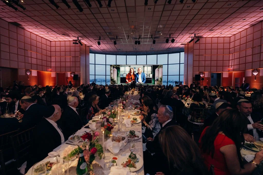 Long banquet tables run the length of the ballroom toward the stage at the Chabad Chestnut Hill gala