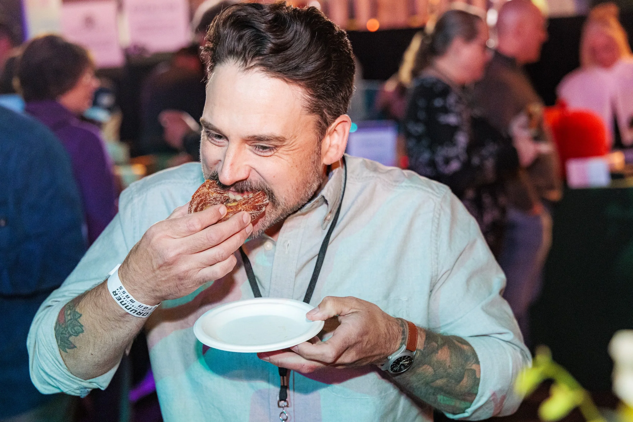 A guest bites into a sandwich at the Spoonfuls Ultimate Tailgate