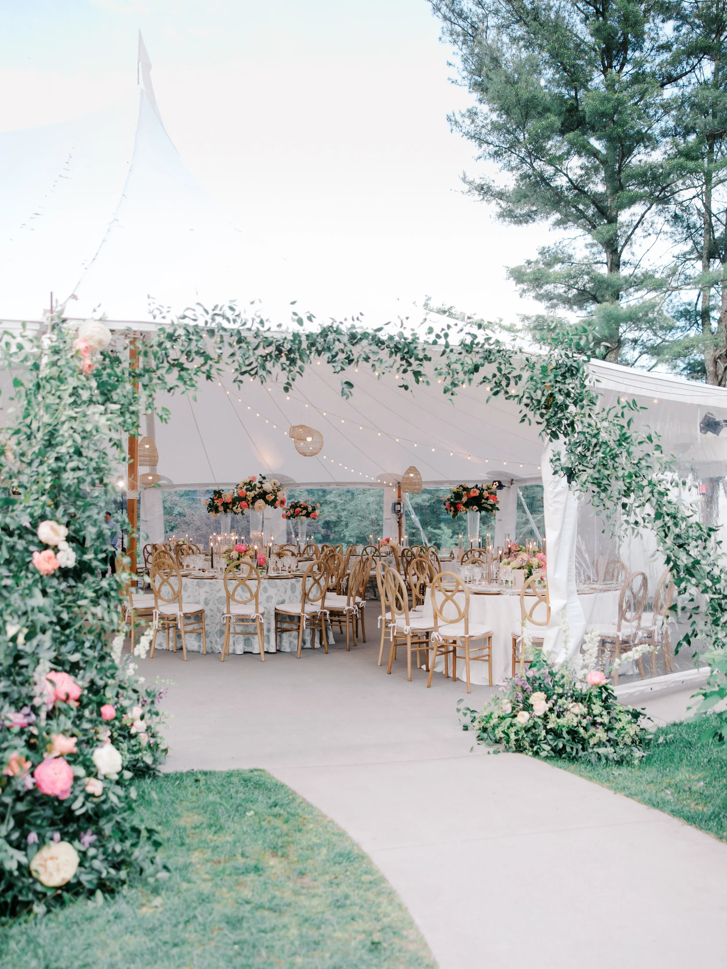 A garden path leads through a floral arch into the reception tent