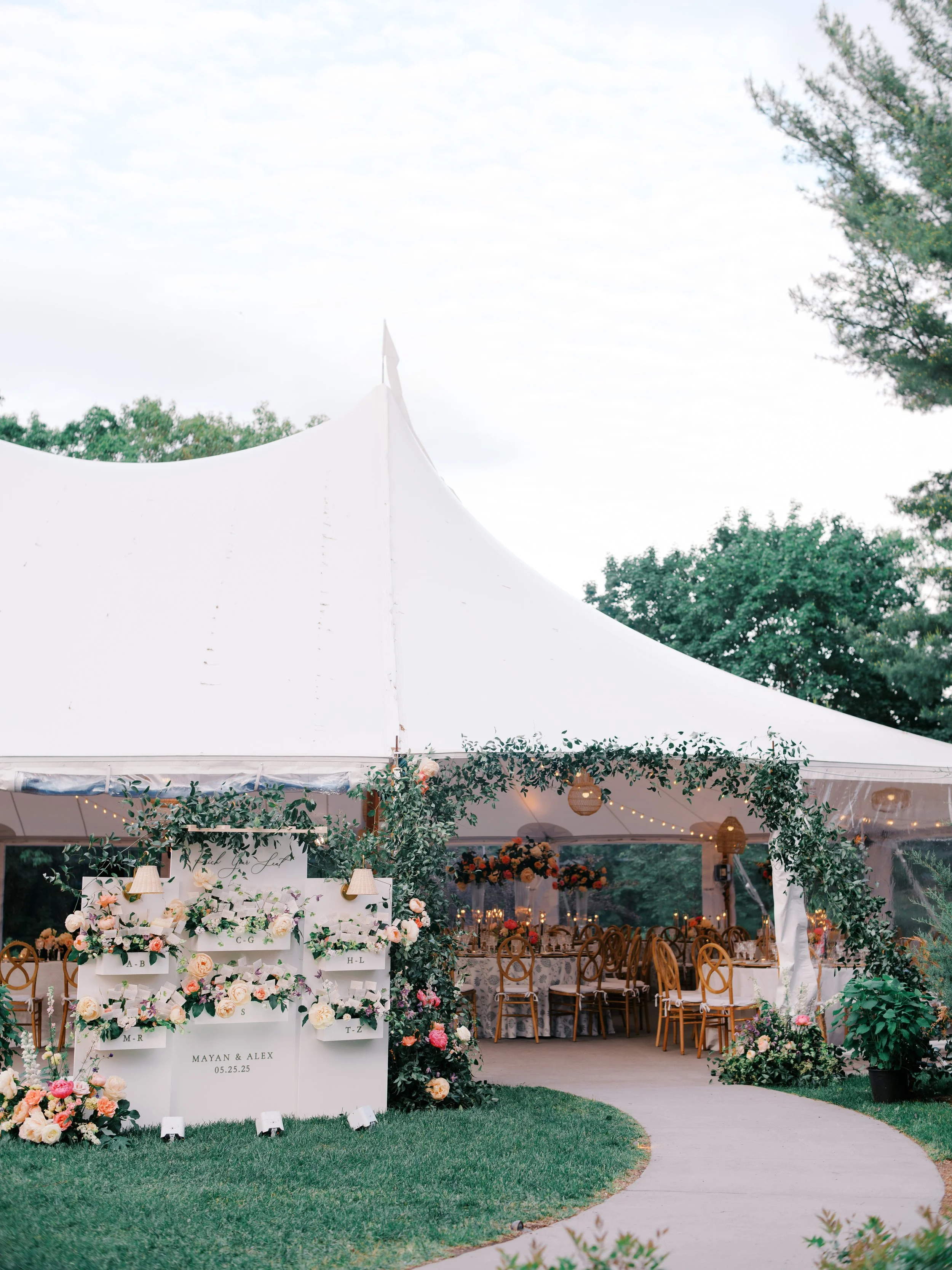 The tent entrance framed by a greenery arch, with the seating display on the lawn