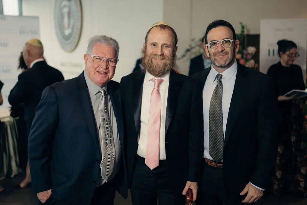 Three guests in suits pose together at the Chabad Chestnut Hill gala