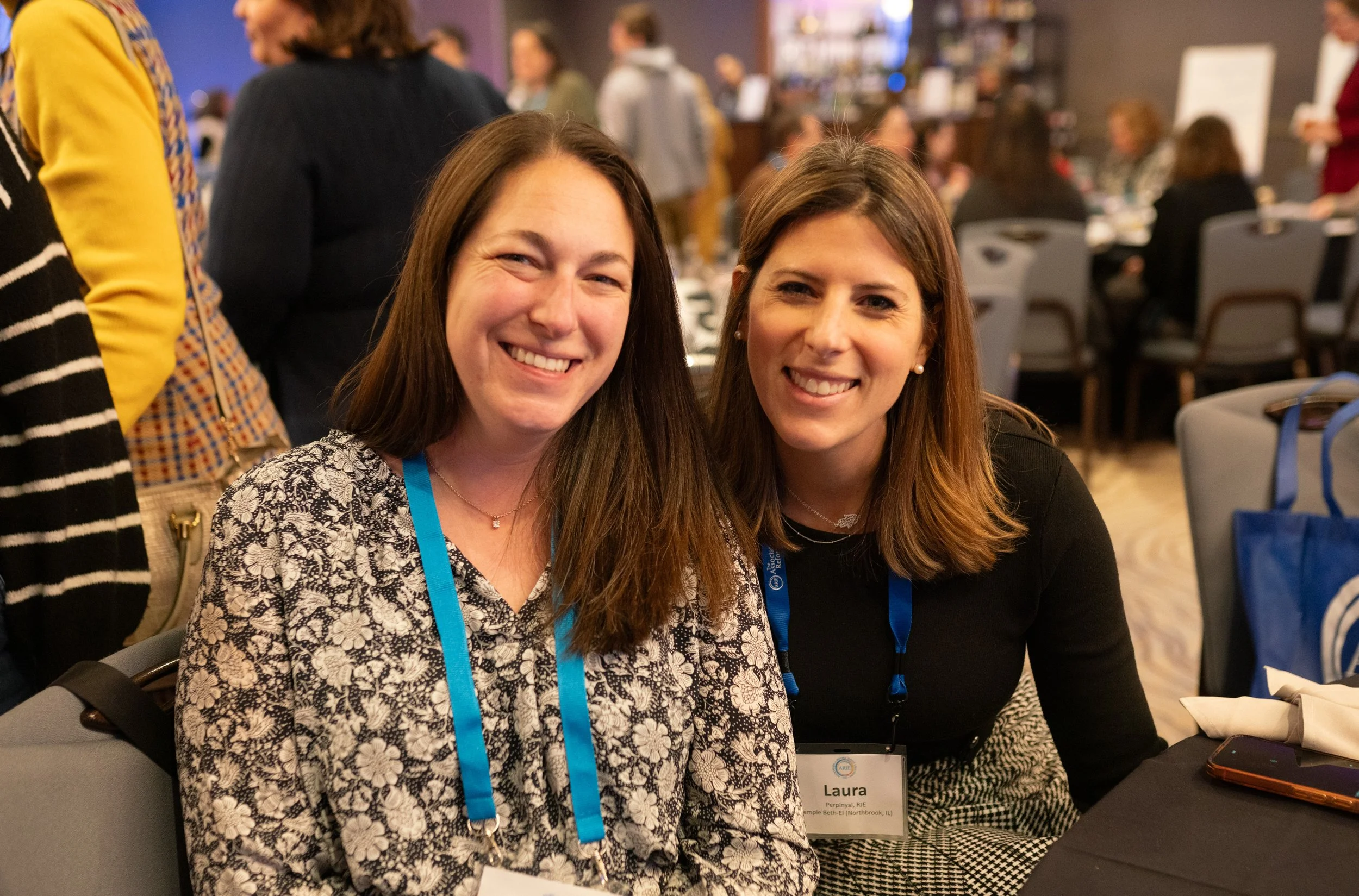 Two smiling attendees seated at a banquet table at the ARJE conference