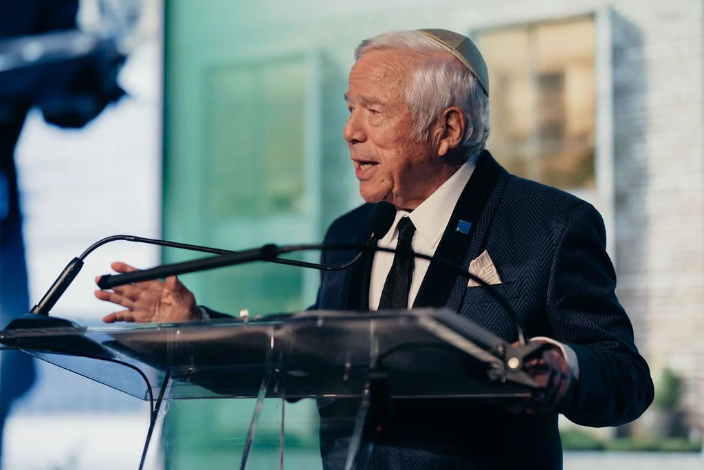 A speaker addresses guests from a glass podium at the Chabad Chestnut Hill 25th anniversary gala