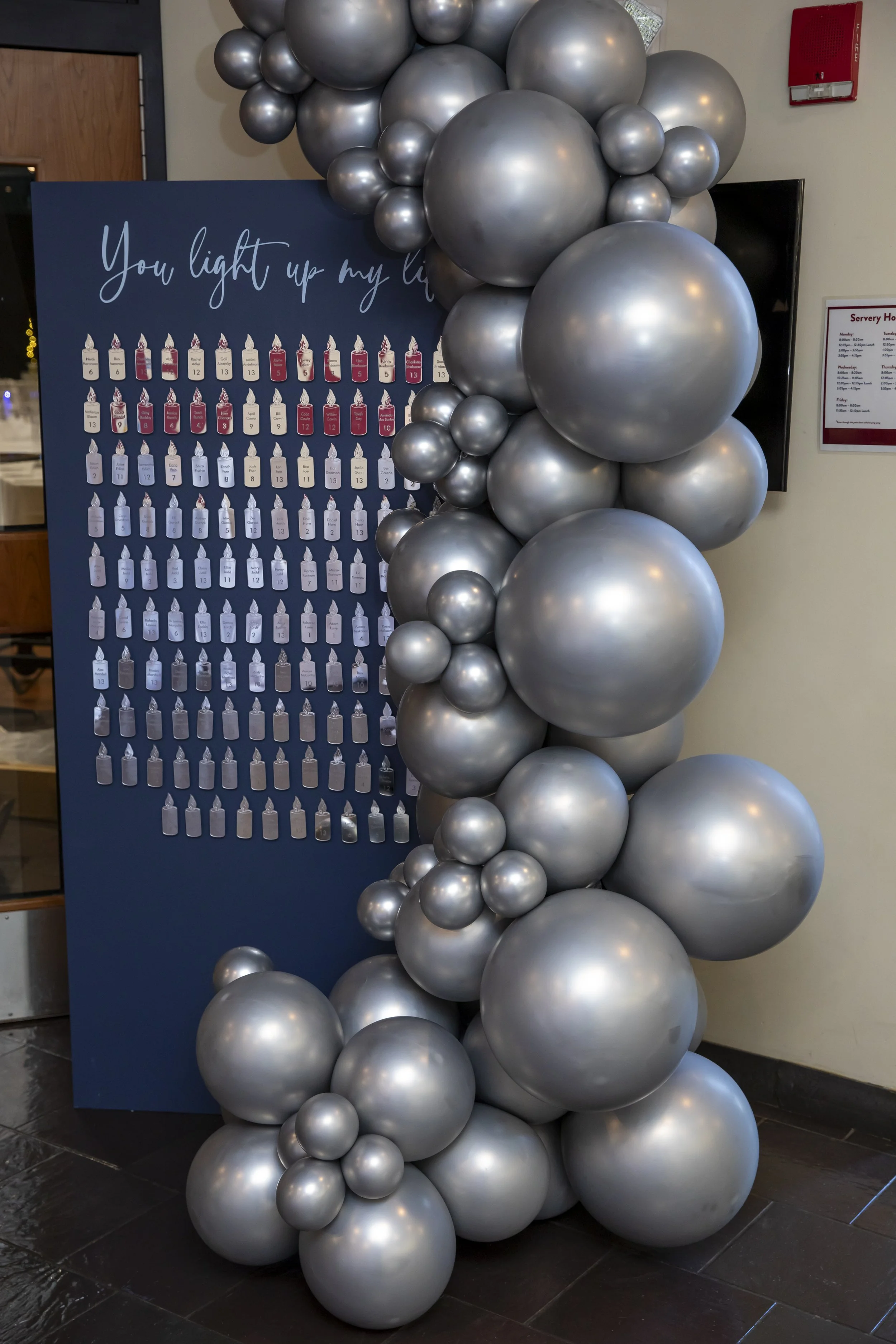 A silver balloon garland frames a navy seating display reading You light up my life at Eloise's bat mitzvah