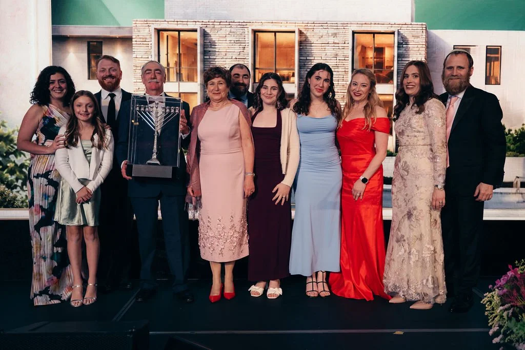 Honorees and family pose on stage, one holding a menorah award, at the Chabad Chestnut Hill gala