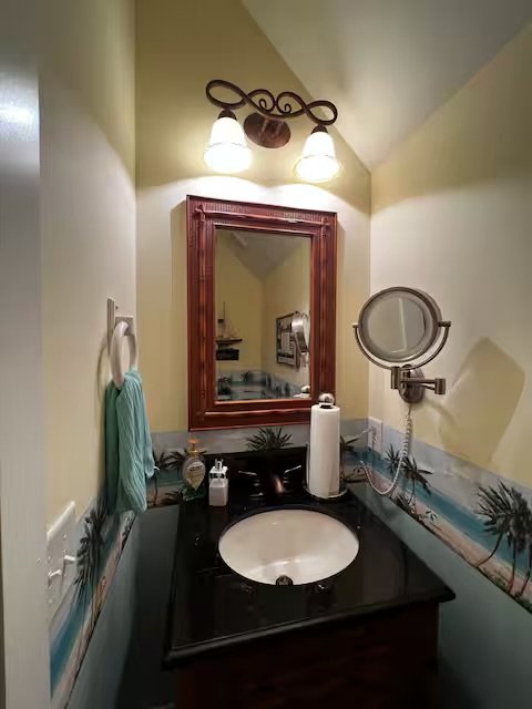Bathroom sink with mirror, wall-mounted magnifying mirror, and light fixtures above