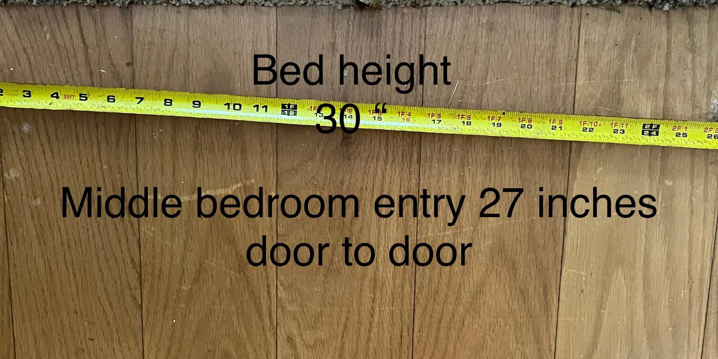 Measuring tape stretched across a wooden door with text indicating bed height and middle bedroom entry dimensions.