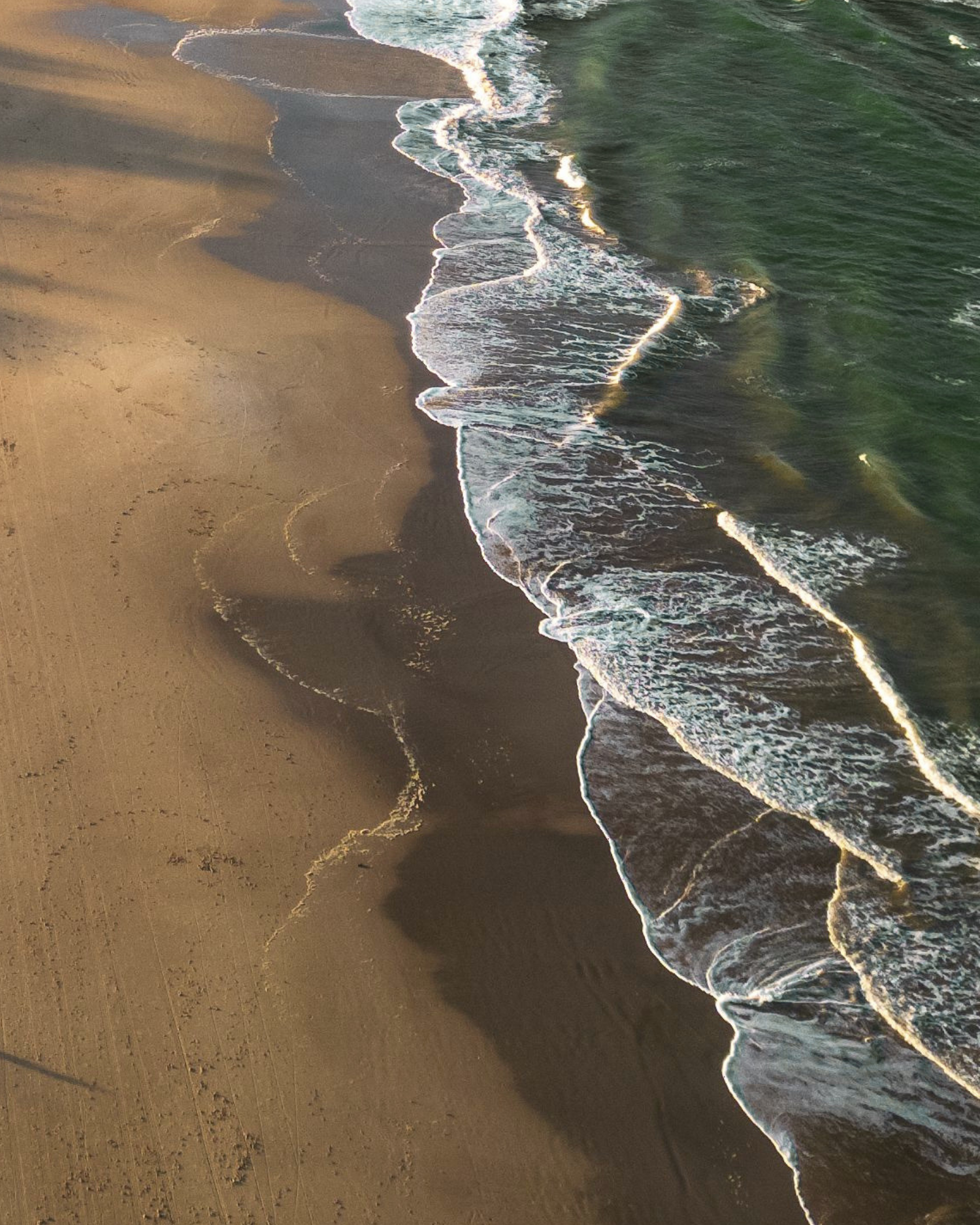 Aerial view of a sandy beach with ocean waves crashing onto the shore.