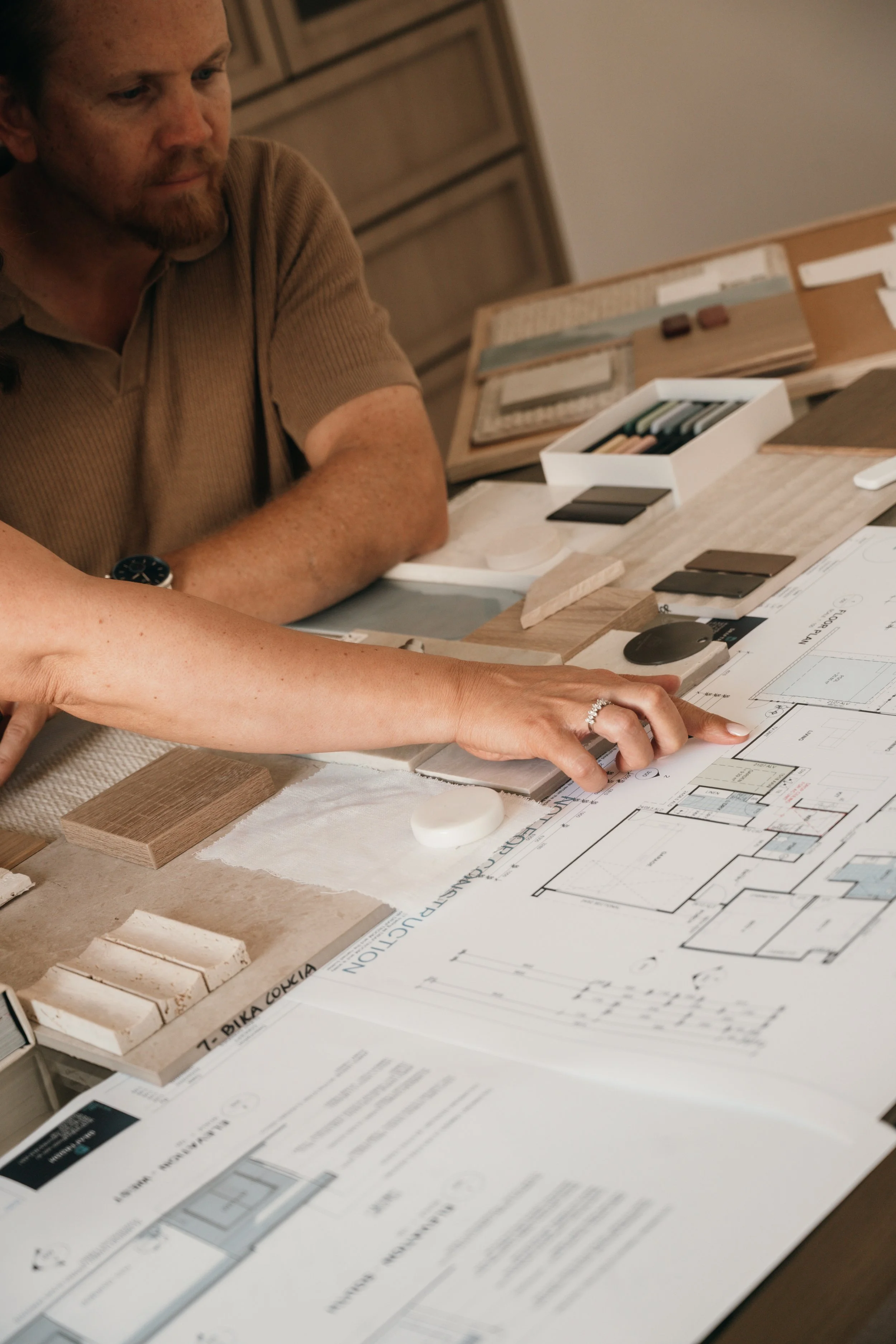 Architects and designers reviewing blueprints and material samples for a construction or renovation project at a work table.