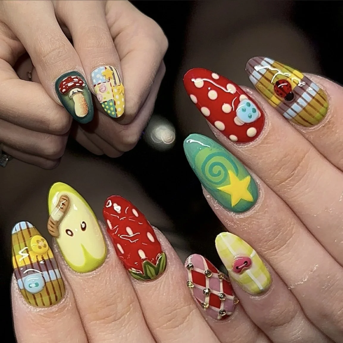 Colorful, whimsical nail art featuring various patterns, characters, and designs on each fingernail, including strawberries, mushrooms, animals, and abstract shapes.