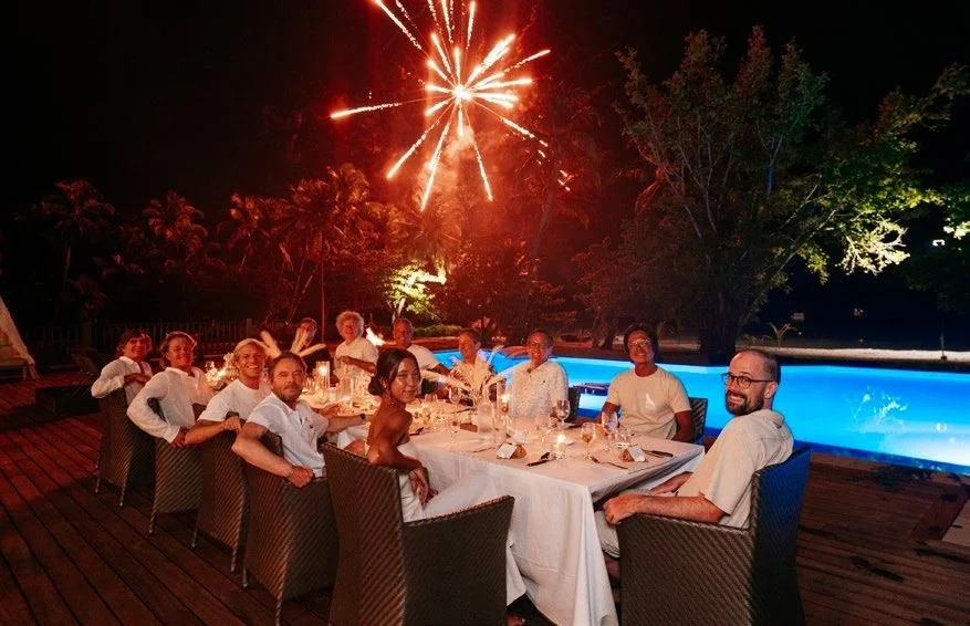 Guests dining beachside with fireworks