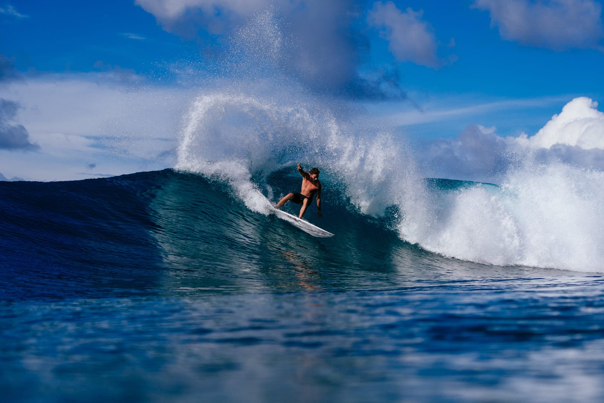 Spray flies off the lip of a wave being ridden near Tanah Mympi.