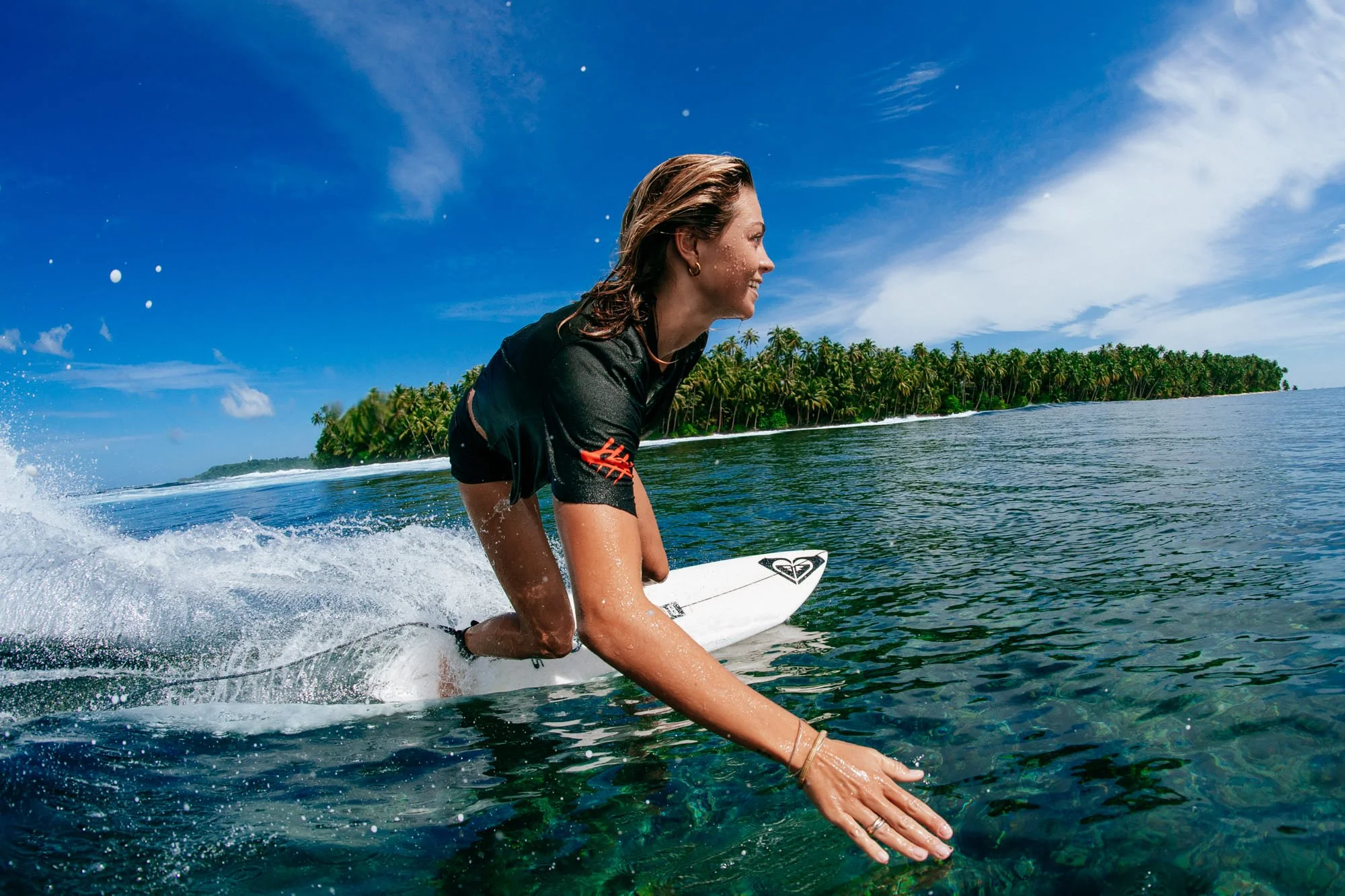 A surfer smiles mid-ride on a wave near Tanah Mympi.