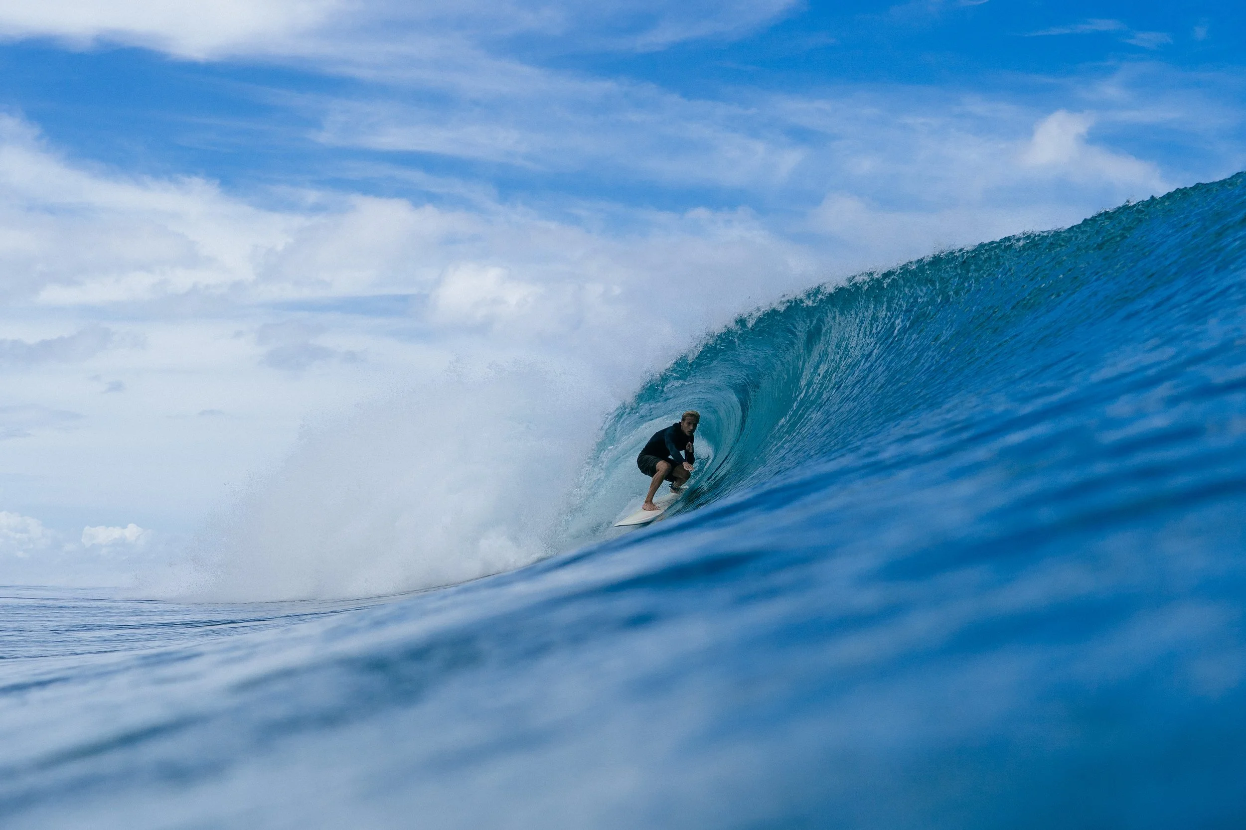 A surfer rides deep inside a barreling wave near Tanah Mympi. Seasonal swell chart: A chart showing seasonal swell patterns and conditions throughout the year near Tanah Mympi.