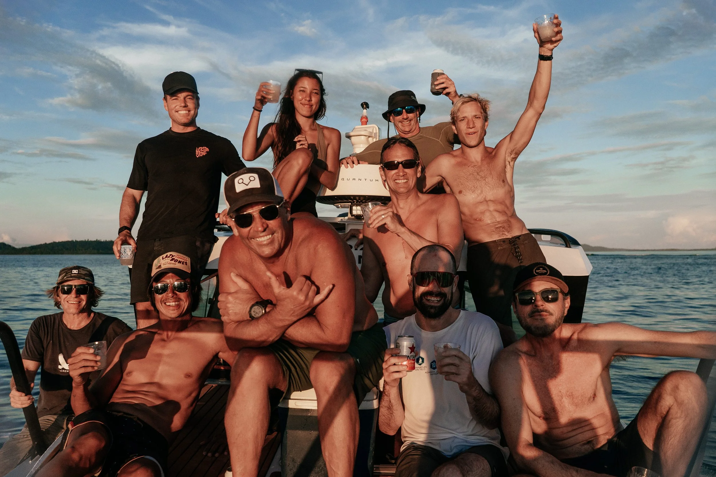 A group of friends pose together on a boat at Tanah Mympi, ocean behind them.