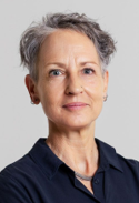 A portrait of a middle-aged woman with short, gray hair wearing a dark blue top, looking confidently at the camera.