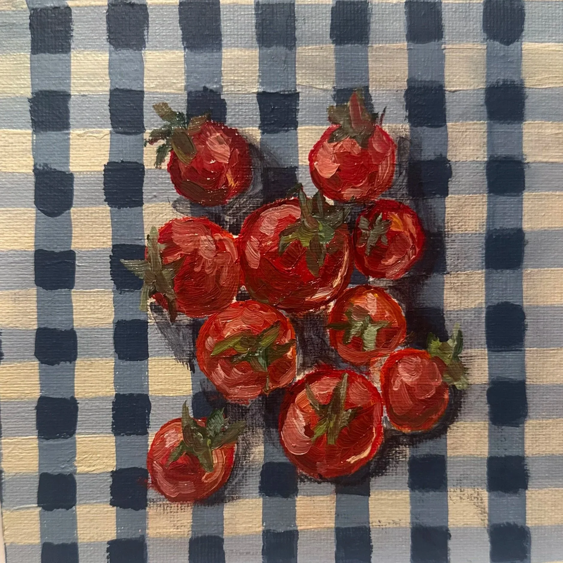 Close-up of a small painting featuring a bunch of red strawberries with green leaves, painted with visible brush strokes, on a checkered background with alternating navy blue and beige squares.