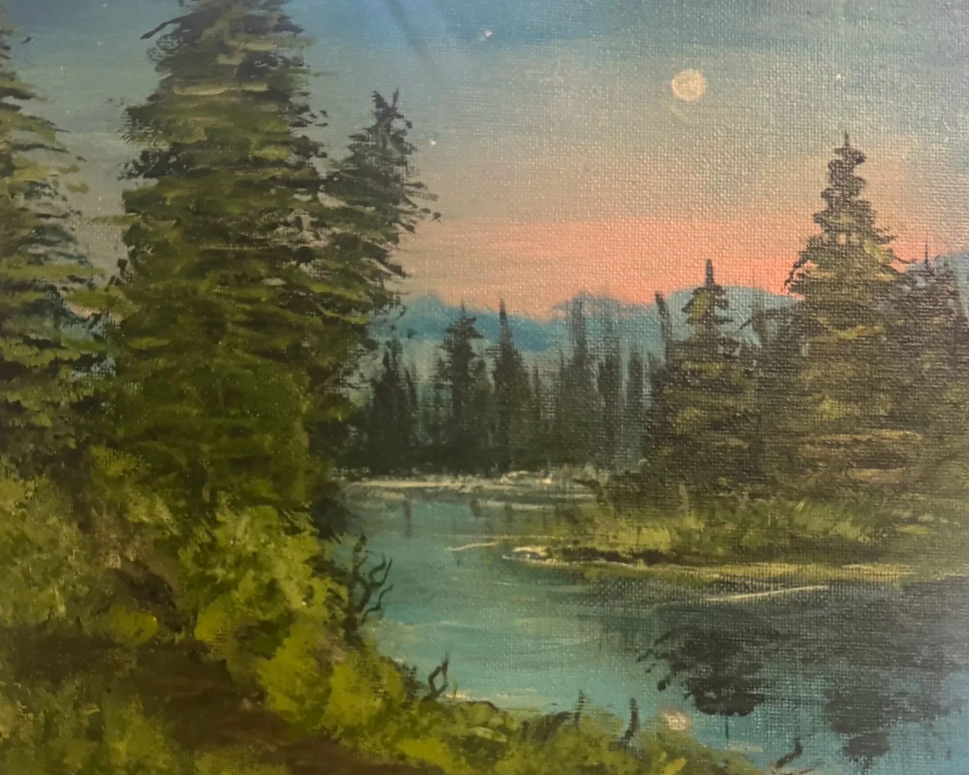 A tranquil landscape with tall evergreen trees along a waterbody, mountains in the background, and a pink-orange sunset sky with a visible moon.