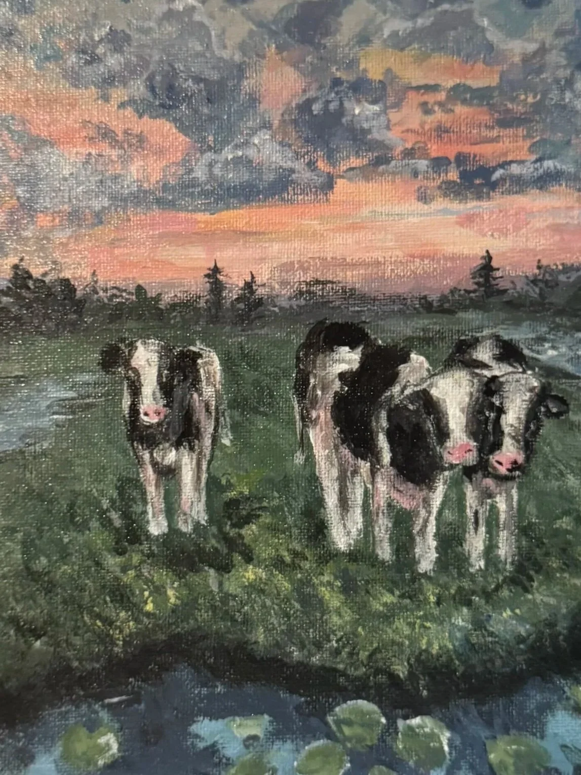 A painting of three cows standing on a grassy field during sunset with a colorful sky and trees in the background.