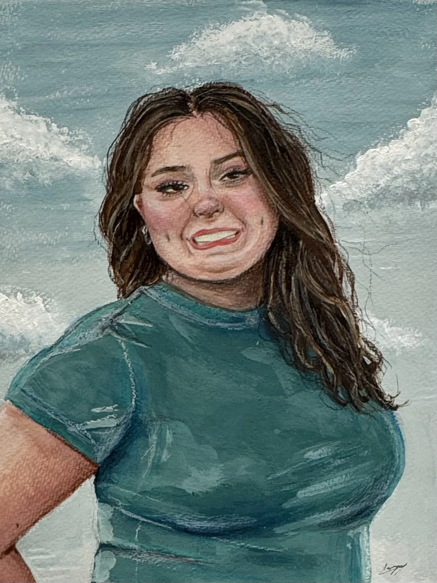 A woman with long brown hair wearing a teal shirt and earrings, smiling at the camera, against a background of ocean waves and clouds.