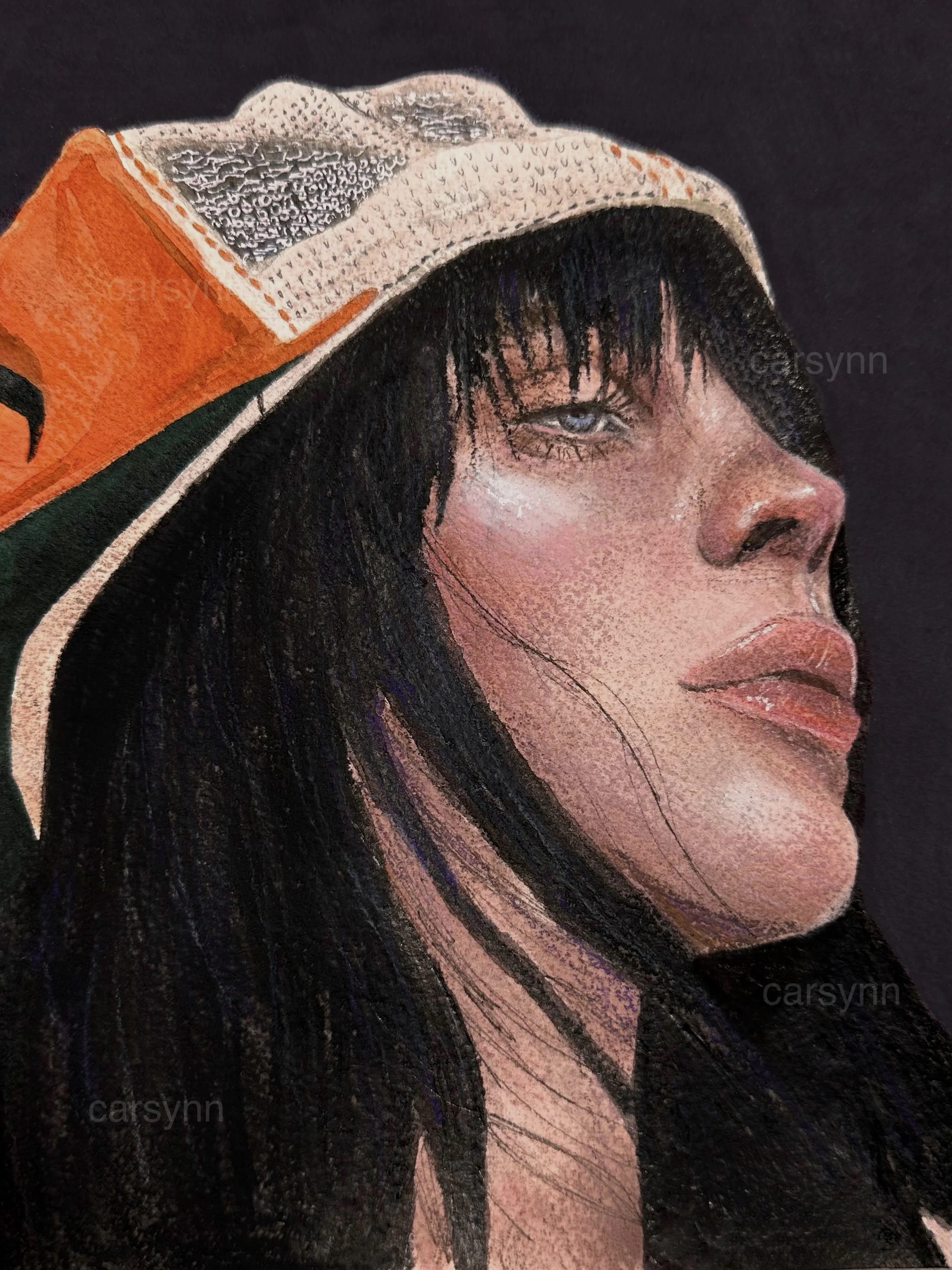 Close-up of a woman's face with long black hair, wearing an orange and white hat with a textured brim and a mesh-like top, against a dark background.