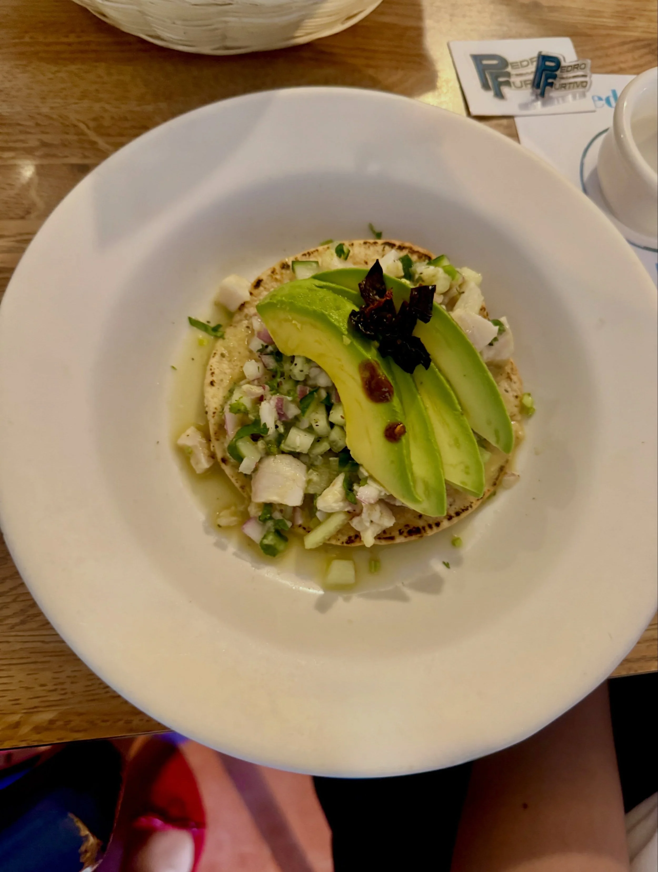 A plate of food featuring avocado slices, a tortilla, and chopped vegetables.